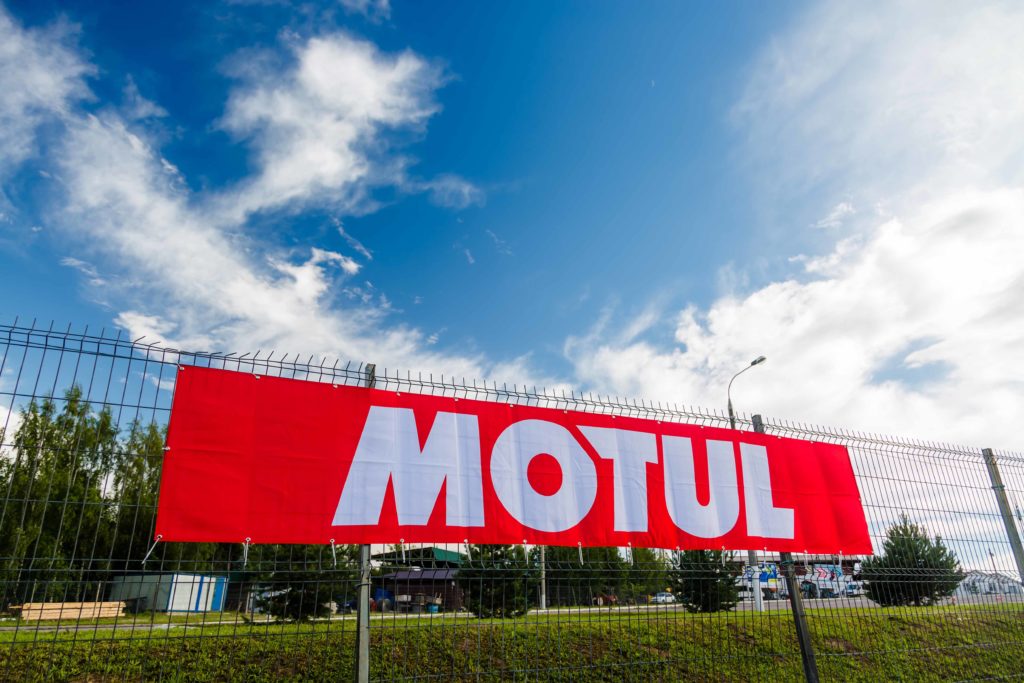 Moscow, Russia - July 06, 2019: Red flag banner Motul hanging on a fence against a blue sky with clouds
